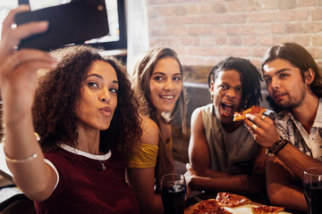 Diverse group of friends enjoying meal and taking selfie
