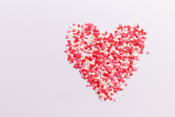 Red, pink and white heart shaped sweets in the shape of a heart scattered on white background. space for text. flat lay. valentine concept