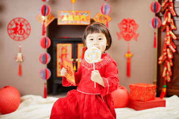 Chinese baby girl  traditional dressing up with a FU means lucky red envelope against all kind of " FU" means" lucky" ornament and greeting card background