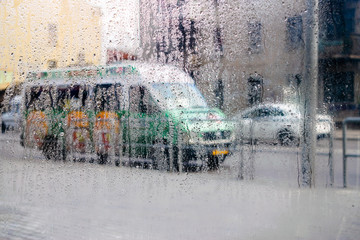  Waking the weather outside the window. Cars drive on a wet road. Drops of water flow down the windowpane. Abstract background
