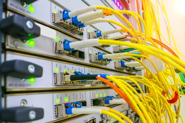 Powerful server equipment datacenter. Yellow fiber optic telecommunications cables are connected to...