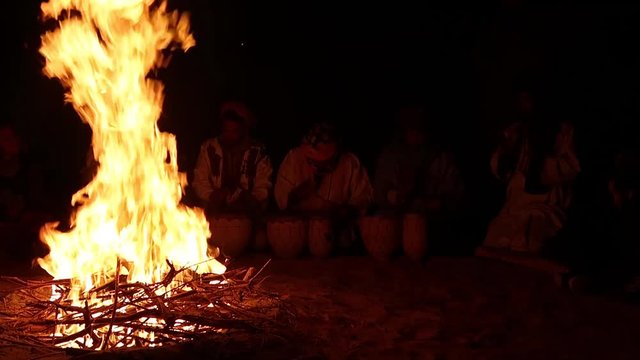 drummers beating their tune around a campfire at night in the sandy dunes