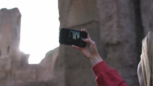 Woman at sunset photographing the ruins of Baths of Caracalla of Roman Empire located in Rome Italy 