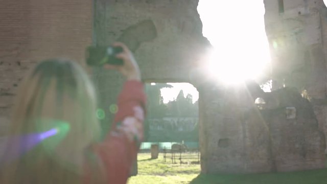 Woman at sunset photographing the ruins of Baths of Caracalla of Roman Empire located in Rome Italy 