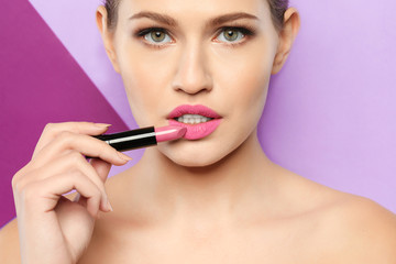 Young woman with beautiful lipstick on color background