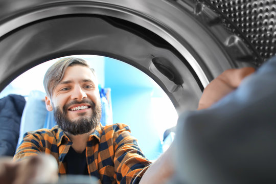 Man Doing Laundry In Laundromat, View From The Inside Of Washing Machine