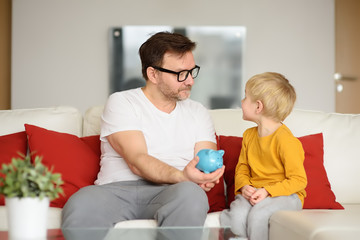 Obraz premium Father and son putting coin into piggy bank