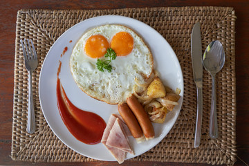 top view of breakfast set with sunny egg and sausage and ham