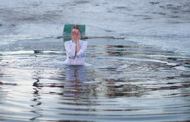 a woman dips into a hole in the lake