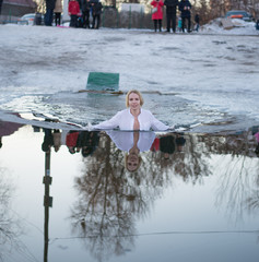 a woman dips into a hole in the lake