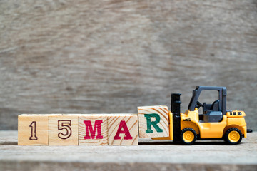 Toy forklift hold block R to complete word 15mar on wood background (Concept for calendar date 15 in month March)