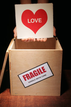 Hands taking a love card out from a box for fragile content