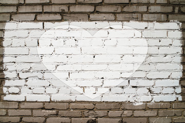 Drawn heart on brick wall with white paint close-up. Mock up. Urban background with painted heart. Imperfect exterior with love symbol graffiti. Valentine day image. Unideal brickwork with copy space.