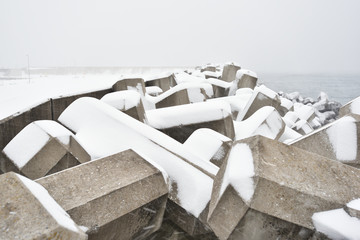 Pier concrete blocks covered with snow in cold winter day