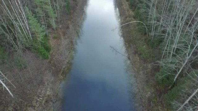 Aerial following calm straight river near Kimola chanal dam, near Kouvola, Finland, during late winter/early spring.