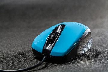 Computer mouse of bright blue color. Black details. Plastic. Modern technologies. Black background. Computer.