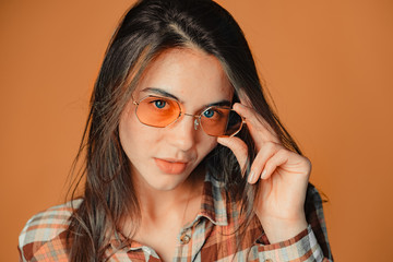 Cute playful young brunette girl making faces on orange background