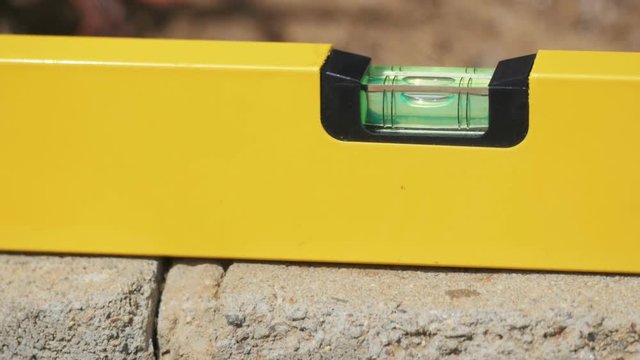 Builders level being placed on a brick wall during construction CLOSE UP