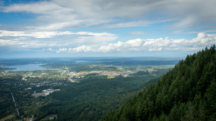 Mountainside Overlook in the Pacific Northwest - with Forrests, Towns and a Lake in the Background and Blue, Cloudy Skies on a Summer Day