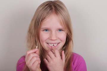 Young girl lost her first bottom front milk teeth. Childhood healthcare concept.
