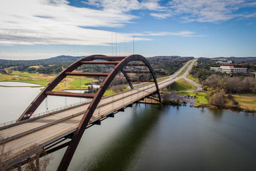 The 360 Pennybacker Bridge in Austin, Texas - with Empty Roads, a Still River and a Blue Sky with Clouds on a Bright and Sunny Day