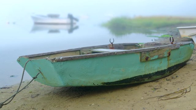 Old rustic wooden rowboat dinghy beached on sandy shore of wetlands