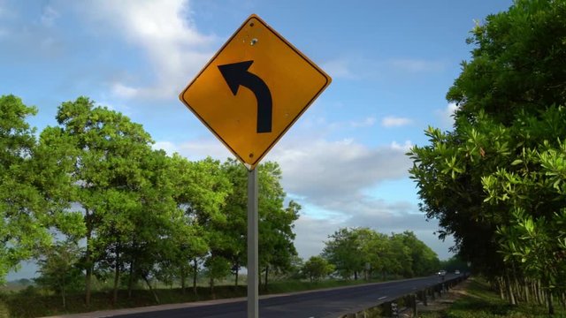 Left curve ahead, direction sign on a highway route with ongoing moving traffic
(medium shot) (moving shot)