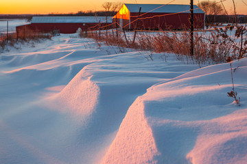 Snowdrifts in a farm lane at sunset.