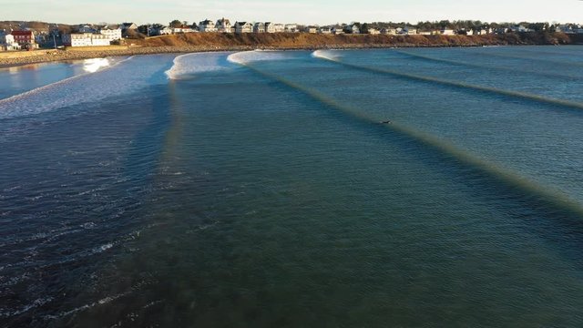 Aerial footage following waves into shore in York Beach Maine on a cold windy December morning with beach houses in the distance
