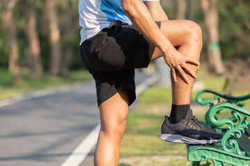 Young fitness man holding his sports leg injury. muscle painful during training. Asian runner having calf ache and problem after running and exercise outside morning. sport and healthy concepts