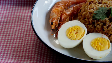 Thai chili paste fried rice, boiled egg and sweet shrimp on white plate and space for write wording, easy cook meal for home making or served in restaurant, popular for foreigner or tourist