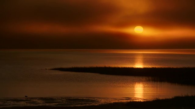 Golden sunset on Cape Cod&permil;&Ucirc;&ordf;s western shore with marshlands and foggy low cloud cover