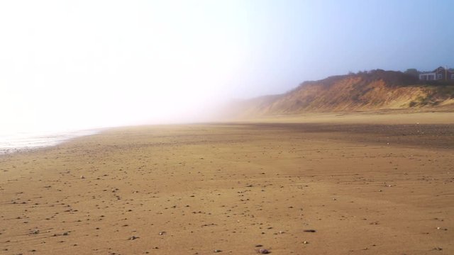 Vacation homes on secluded empty beach at sunrise or sunset - camera pans right