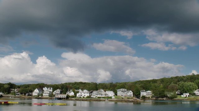 Row of seasonal rental homes at Boothbay Harbor, Maine on a nice summer day with beautiful clouds in the sky. Camera pans left.