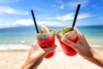 Fresh watermelon juice with a straw in two glasses against a bright tropical landscape, against the background of the sea. Vacation vacations healthy food concept