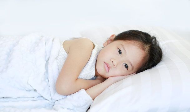 Adorable beautiful Asian child girl lying on bed with looking at camera.