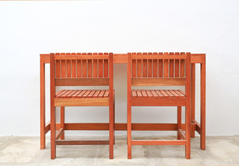 Hardwood furniture, Indoor wooden chair and table set against white cement wall background.