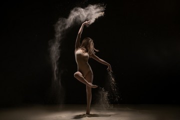 Fototapeta na wymiar Sexy girl dancing gracefully in white dust cloud