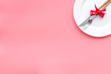 Dating on Valentine's day concept. Festive dishes, tableware on plate on pink background top view space for text