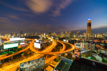 Fototapeta na wymiar Panoramic Bangkok City with Curved Express Way and Skyscraper. Top View of City Elevated Highway with Car Traffic Light Trial at Twilight Time.