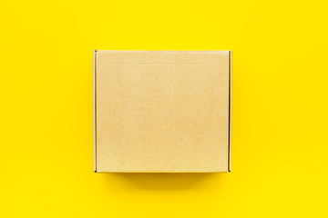 Delivery concept. Cardboard box on yellow background top view mockup