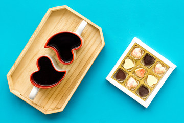Dating on Valentine's day concept. Heart-shaped mugs and sweets on blue background top view