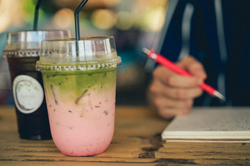 close up image of ice drinks with blur male hands writing at notebook background.