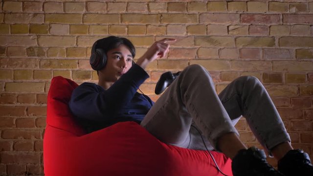 Closeup portrait of young korean man playing video games using console getting happy winning and celebrating