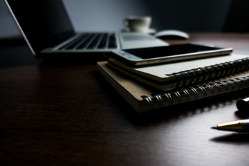 Close up office desk table with laptop, note book, mobile coffee and pen. Selective focus. Business concept. Copy space.