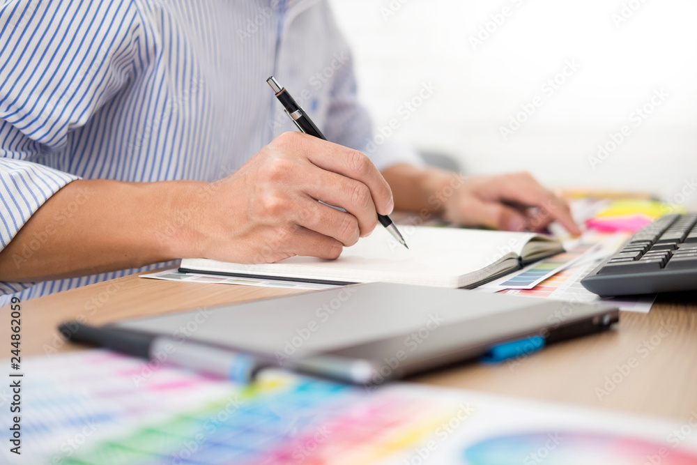 Aufkleber designer editor at work drawing sketches a new project on graphic tablet and color palette sitting a
