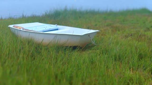 Little rowboat beached in dune grass wetlands at low tide.