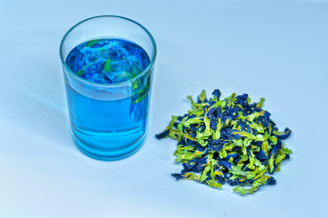 Butterfly pea flower dry tea and glass served into a transparent cup purple blur light space background. Blue herbal tea