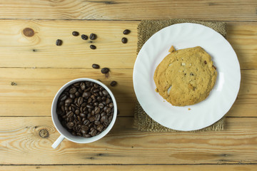 Coffee bean in cup and cookie on wooden table,selective focus.