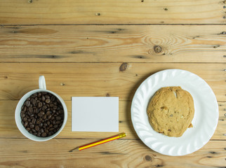 White paper note,coffee cup and cookie on wooden table,soft focus.